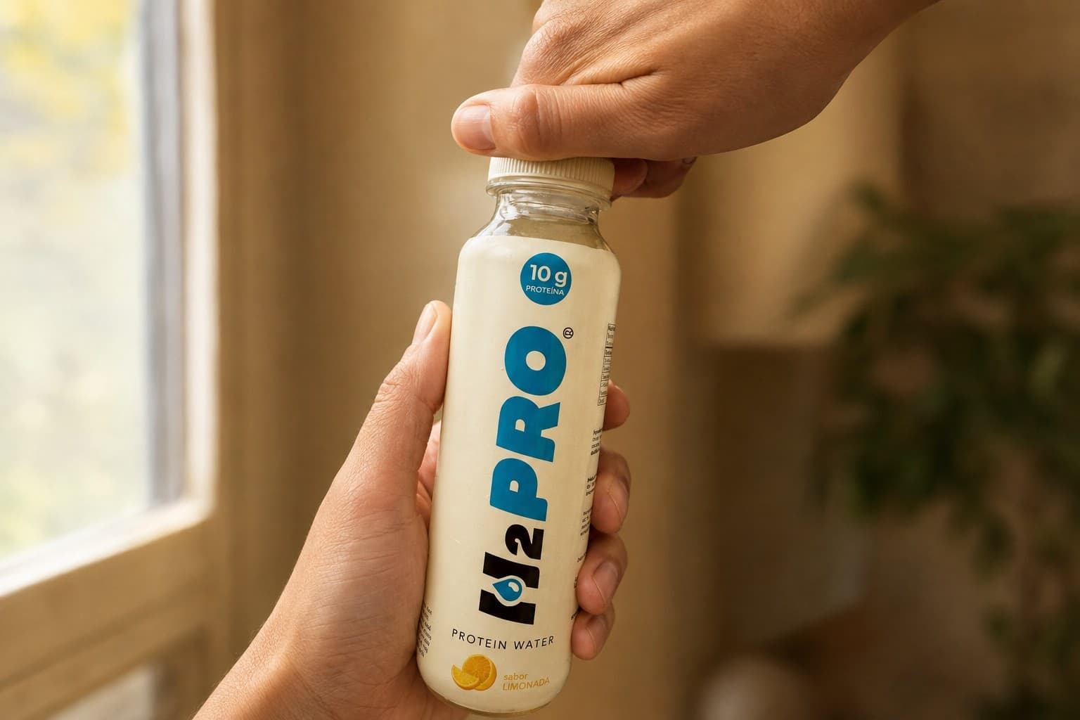 Manos abriendo la tapa de una botella H2PRO — una vuelta y lista para tomar